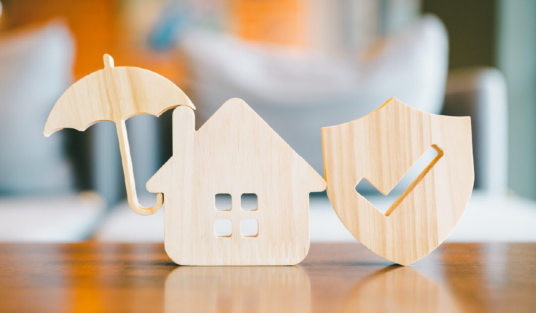 A wooden icon of a home beside an umbrella and a shield